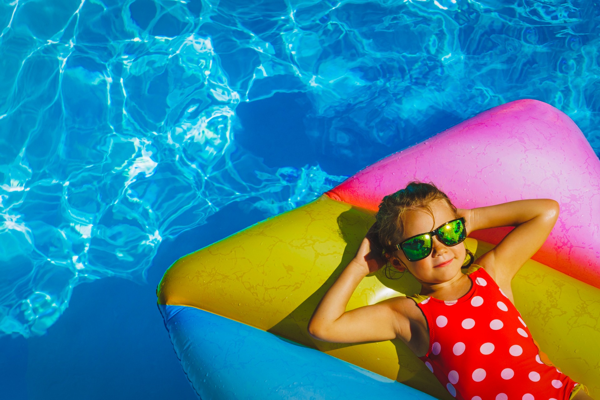 A child in a pool holding a yellow float