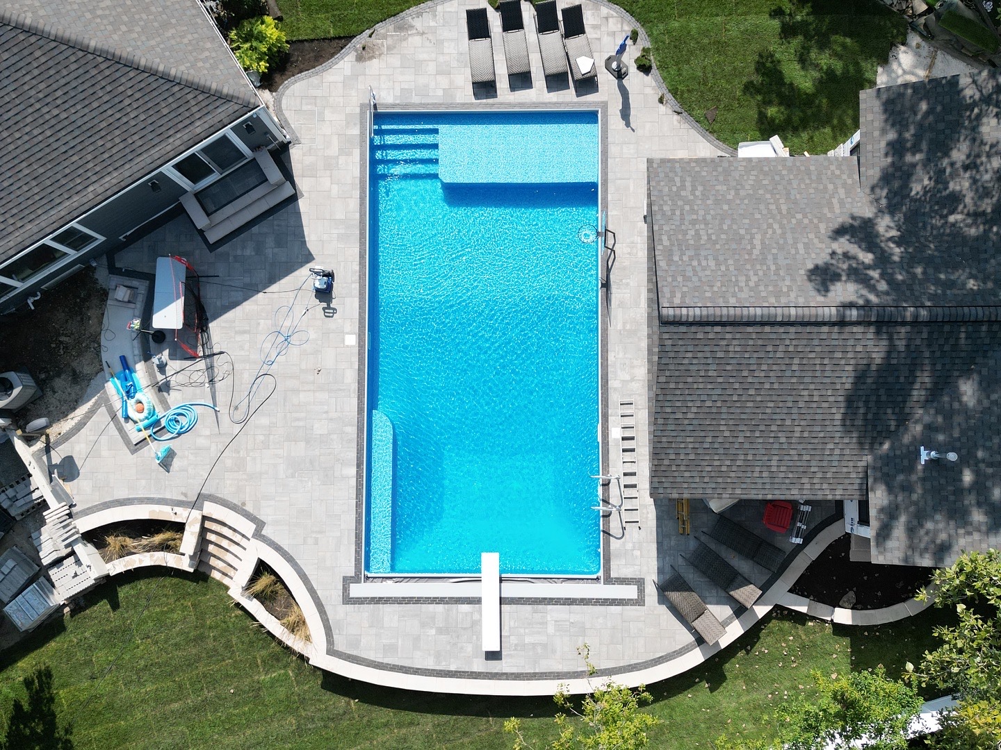 Rectangular inground pool with a light deck and patio chairs