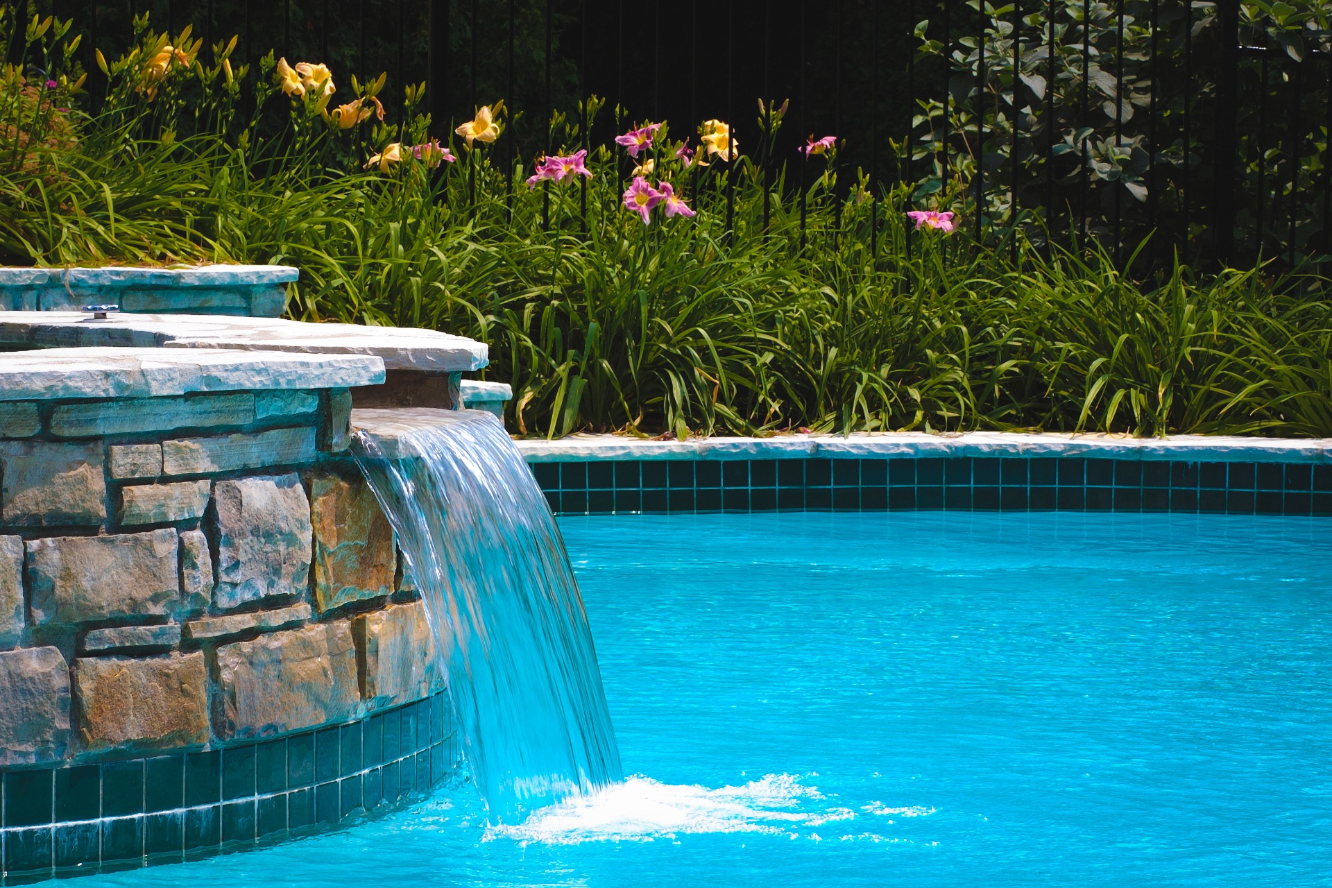 Inground pool with a wide stone waterfall
